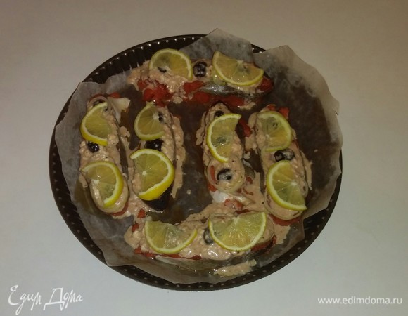 Затем противень застилаем бумагой для выпечки и смазываем ее оливковым маслом. Лимон нарезаем кружочками из расчета 1 кружок на 1 кусочек рыбы. Затем разрезаем кружочки лимона пополам. Так же порционно нарезаем репчатый лук. Затем колечки репчатого лука распушаем руками. Маслины нарезаем половинками. Затем на противень выкладываем кусочки рыбы, на них — репчатый лук, дольки лимона и половинки маслин. Затем поливаем кусочки рыбы соусом. Ставим противень с рыбой в разогретую до 180°C духовку на 20 минут (время зависит от вашей духовки). Перед подачей на каждую тарелку кладем лист китайского салата, а на него уже кусочек запеченной рыбы. Приятного аппетита!