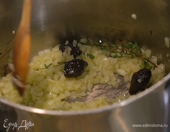 Почистить 5 зубчиков чеснока, мелко порубить, выложить в кастрюлю с луком и перемешать, затем добавить чернослив, лавровые листья, веточки тимьяна и все обжарить до мягкости.