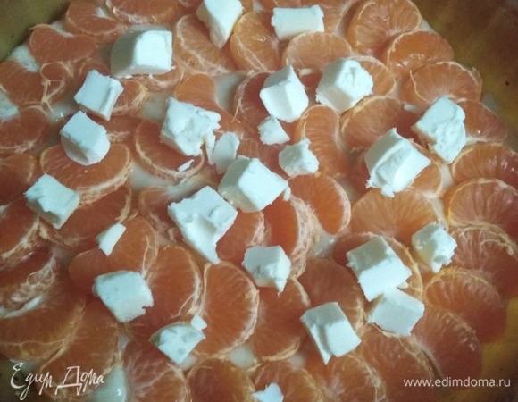 На тесто выложить дольки мандаринов и рубленное на кусочки сливочное масло.