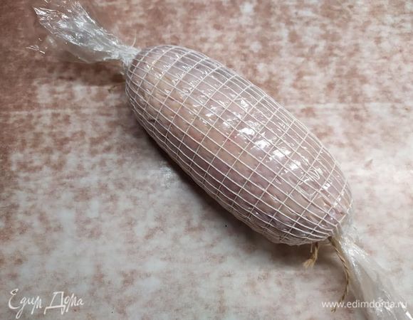 Закручиваем рулет в пленку для запекания (получается «конфетка»). Концы завязываем колбасной веревкой или кухонной нитью. Я использую формовочную сетку, но это необязательно. Кладем в холодильник на 12–24 часа. Поскольку в специях есть нитритная соль, то мясо должно немного вызреть (как это делают с ветчиной).