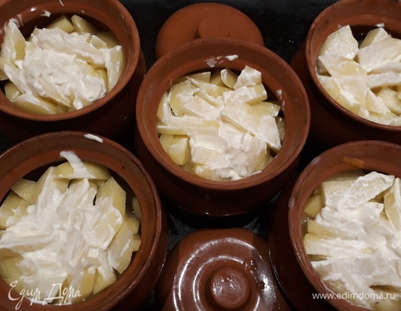 В горшочки сначала кладем мясо с грибами и пережаркой, затем — картофель. Наливаем водички в каждый горшок, но не больше, чем до середины горшка. Солим картофель сверху и смазываем майонезом. Закрываем горшочки и отправляем в разогретую до 180–200°C духовку примерно на 25 минут.