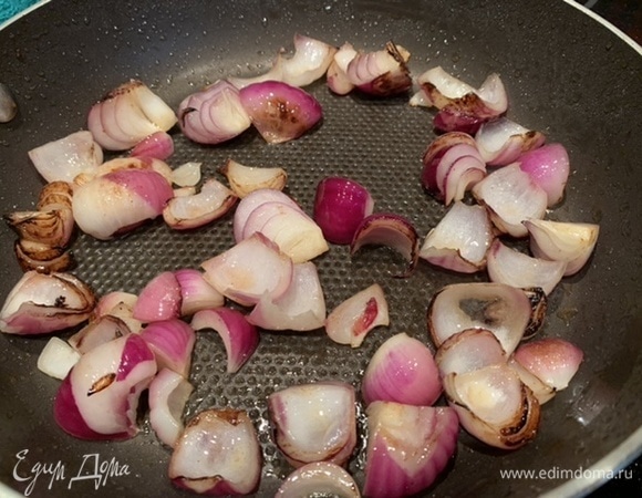 Красный лук нарежьте на четвертинки и так же обжарьте, выложите в тажин.