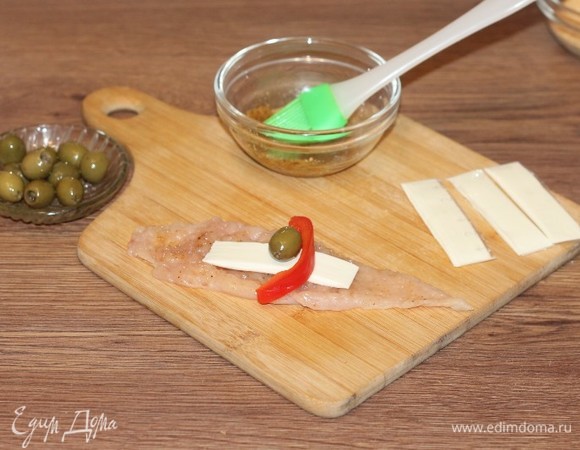 Положите на полоску кусочек сыра и оливку.