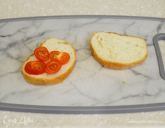 На один ломтик хлеба выложите с одной стороны нарезанные помидорки. Можно взять и большой помидор, тогда понадобится один кружок помидора.