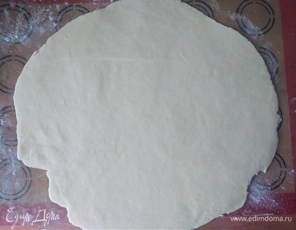 Духовку разогреть до 170°C. Охлажденное тесто раскатать (если нужно, посыпать мукой) в круг. Лучше это делать сразу на коврике или бумаге.
