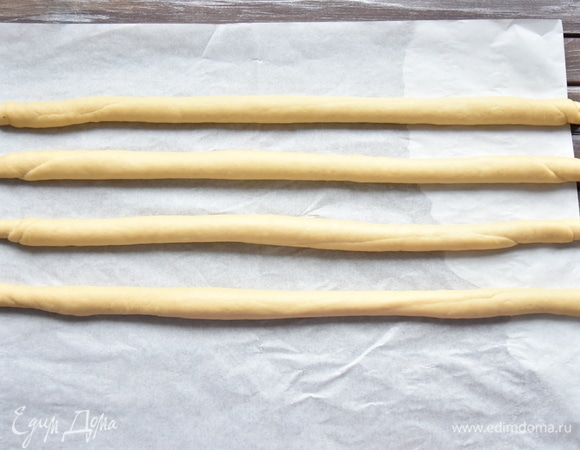 Для точности тесто взвесить и разделить его на четыре части, одинаковые по весу. Каждую часть скатать в шар, накрыть пленкой и оставить на 30 минут. Затем из шариков теста раскатать жгуты одного размера (38–40 см). Оформлять изделие удобнее сразу на пергаменте, чтобы легче его было перенести на противень.