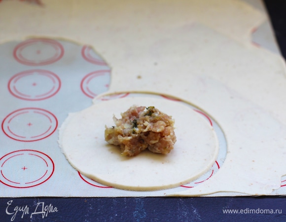 Так как тесто быстро сохнет, его кладут на влажное полотенце и им же накрывают. Вырезаем большой круг с помощью пиалы, у меня диаметр — около 8 см, кладем немного начинки. Не старайтесь набить побольше начинки, так как не останется сверху теста для юбочки.