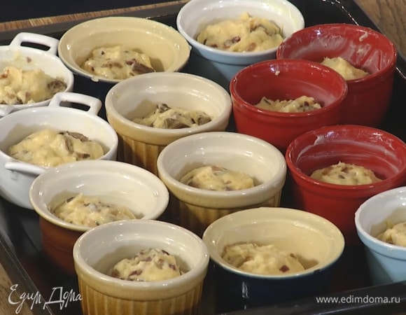 В подошедшее тесто добавить теплые грибы и вымесить его руками, затем разложить в смазанные оставшимся сливочным маслом керамические формочки, заполняя их на 2/3 объема, поместить на противень, накрыть влажным полотенцем и оставить на 15 минут.