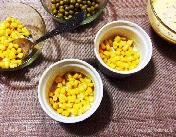 Смазать керамические формочки небольшим количеством оливкового масла и выложить по столовой ложке консервированной кукурузы в каждую.