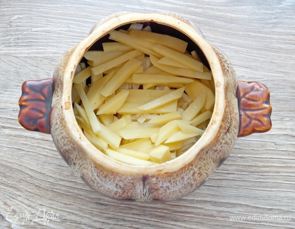 Картофель чистим, моем, режем соломкой и добавляем в горшочек.
