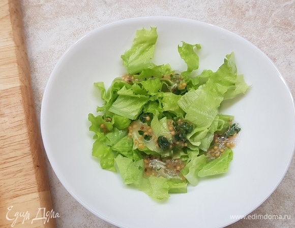 На дно салатника положить салатные листья, полить частью заправки.