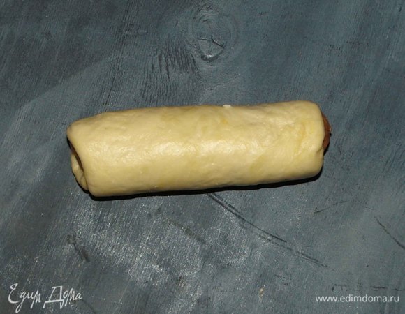 Завернуть сосиску в тесто. Перевернуть швом вниз.