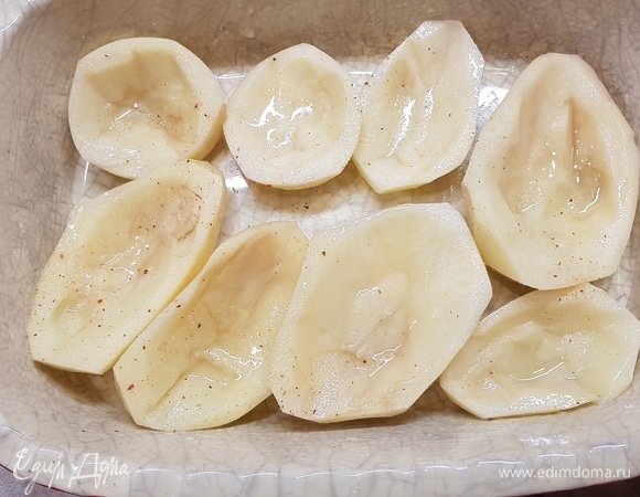 Картофель очистить, вымыть, разрезать пополам. Из каждой половинки убрать середину. Получится что-то похожее на лодочку. Смазать каждую картофелину маслом, посолить и поперчить. Поставить запекаться в духовку на 20 минут при 200°C.