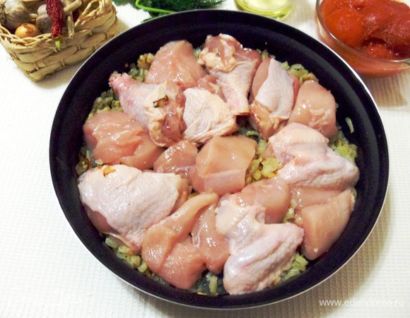 Затем к жареному луку выложить кусочки курицы.