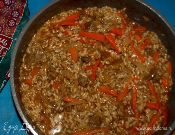 Готовим, пока рис не впитает всю воду. Не забываем помешивать. Рис должен получиться мягким, но внутри быть чуть твердым. По консистенции будет напоминать ризотто. Пока блюдо доходит на огне, подготовим лук. Такой лук называется отбитым. Половину луковицы, которую откладывали, режем полукольцами. Нарезанный лук мнем руками, пока он не станет мягким. Промываем холодной водой, чтобы ушла лишняя горечь, но острота осталась.