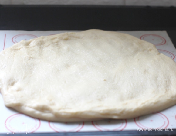 На тефлоновом коврике раскатать тесто в лепешку диаметром 25 см. Накрыть полотенцем и поставить в тепло. Например, в теплую духовку на 20 минут.
