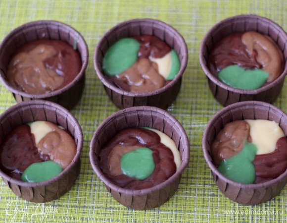 В формочки для капкейков выкладываем тесто из разных мешков в произвольном порядке. Формочки заполняем не больше чем на 2/3, тесто хорошо поднимается в процессе выпечки. Ставим в духовку, разогретую до 180°C, на 25–30 минут. Ориентируйтесь по своей духовке и проверяйте зубочисткой.