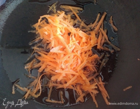 Приготовить начинку. Разогреть масло в сковороде. Всыпать тертую морковь, готовить минуту.