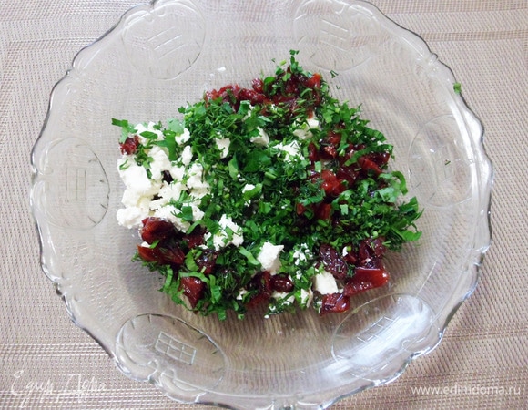 Вяленые сливы нарезать мелкими кусочками, фету нарезать мелкими кубиками, чеснок измельчить. Переложить все ингредиенты в миску и добавить рубленую зелень.