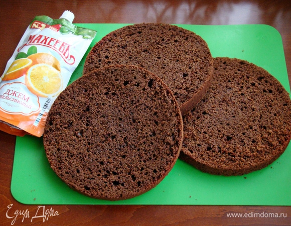 Остывший бисквит разрезать на три коржа. Бисквит получается мягким и в меру сочным, поэтому не требует дополнительной пропитки. На блюдо установить кольцо и поместить нижний корж.