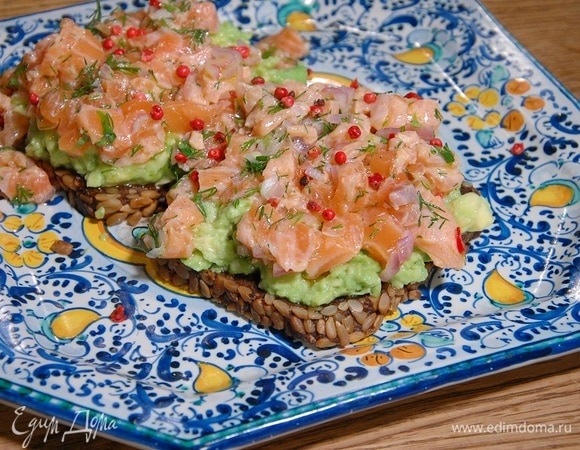 На хлеб выложить размятое авокадо и тартар из семги, посыпать розовым перцем.
