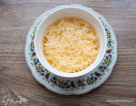 Сыр натираем на мелкой терке. После звукового сигнала вынимаем форму и посыпаем верх сыром.