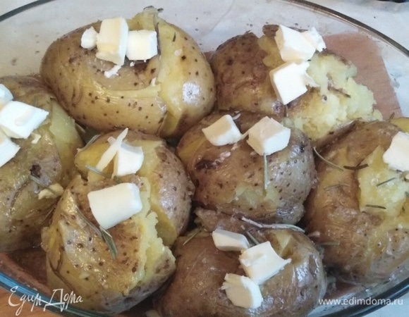 Выложить картофель. Смазать его оливковым маслом. Посолить. Добавить розмарин. Выложить на каждую картошку кусочки сливочного масла. Поставить в заранее разогретую духовку.