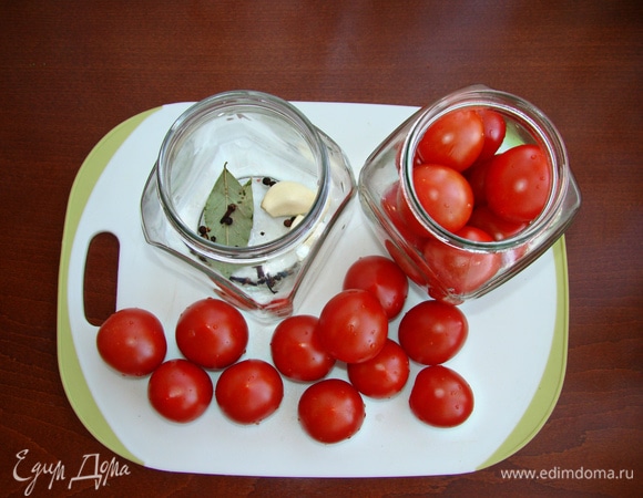 На дно банок уложить по лавровому листу, по паре зубчиков чеснока, перец горошком, гвоздику и плотно уложить в банки помидоры черри. Количество ингредиентов рассчитано на две банки объемом 0,7 л.