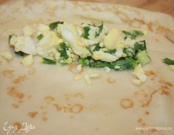 Лук зеленый и вареные яйца порубить. Все смешать и посолить по вкусу. Готовую начинку выкладывать порциями на край блина.