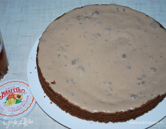 Смажьте первый корж обильно кремом (крем не густой и хорошо пропитает коржи). На фото видно, что в креме есть кусочки не растаявшего шоколада.