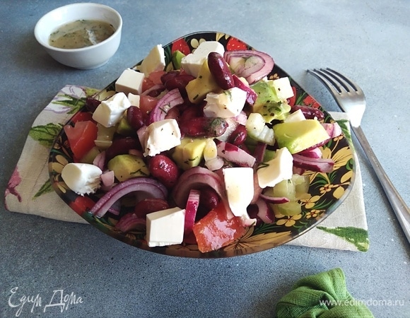 Салат полить заправкой и перемешать. Фету нарезать кубиками и разложить сверху.