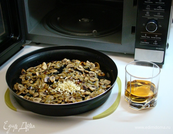 К обжаренным луку и грибам добавить измельченный чеснок и влить белое сухое вино. Перемешать и выпарить при средней мощности (600 Вт) в течение 5 минут.