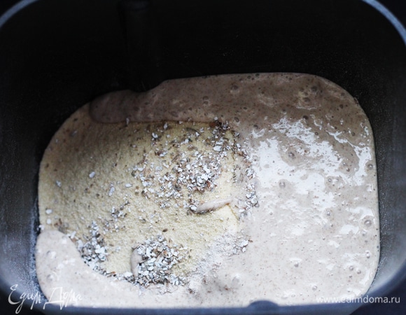 Теперь, когда опара созрела, нужно правильно замесить тесто. Включаем режим «Пельмени». Автолиз. Смешиваем всю опару, 100 г воды (остальные 50 г пока не добавляем), всю муку и отруби, перемешиваем в грубую массу, накрываем, чтобы не сохла, и оставляем на 30–40 минут. Начинаем замес. Сначала тесто будет довольно влажным и липким, но по ходу замеса будет становиться все более эластичным. Через 15 минут замеса в хлебопечи я добавила холодное сливочное масло (замерзшее, прямо из холодильника) и соль. Как только я добавила соль, тесто сразу стало упругим, перестало размазываться по ведерку, все подтянулось и собралось в колобок. Как только тесто сошлось в колобок, постепенно начинаем вливать воду. Я добавляла порциями в четыре подхода. Каждую новую порцию воды вливала после того, как тесто полностью впитало предыдущую и снова сошлось в колобок. На это ушло минут 5–7 от силы.