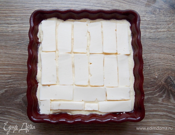 Наливаем еще 1/3 теста и разравниваем, закрывая первый слой сыра. Плавленый сырок тоже режем тонкими пластинками и раскладываем на всю поверхность второго теста. Если не любите сырки, возьмите плавленый сыр пластинками.