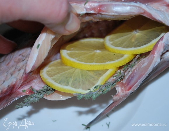 Очистите рыбу от чешуи и выпотрошите. Промойте ее хорошо, затем обсушите салфеткой. Начините брюшко рыбы ломтиками лимона, веточкой тимьяна и розмарина.