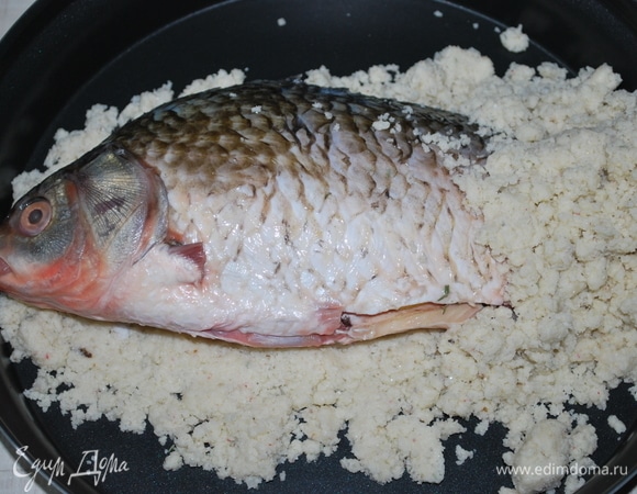 Выложите часть соляной смеси и на нее положите рыбу (я это сделала в чаше для микроволновой печи). Накройте сверху оставшейся смесью и обомните, чтобы она плотно прилегала к рыбе.