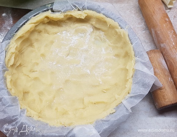 Достать тесто из холодильника. Форму (у меня 24 см) застелить бумагой для выпечки. Выложить тесто в форму, распределить по ней, сформировать бортики.