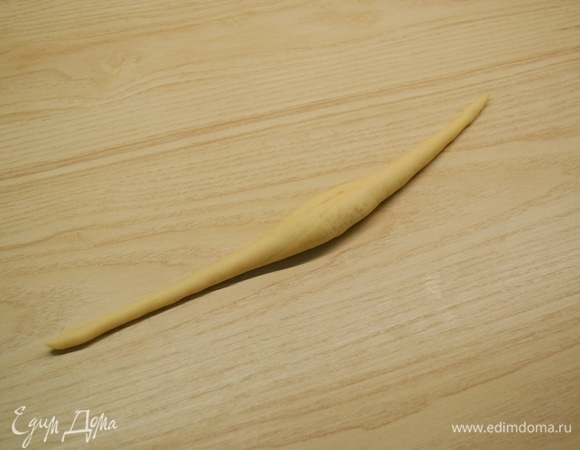 Тесто разделить на кусочки по 60 г. Каждый кусочек теста раскатать в жгут таким образом, чтобы в середине жгут был чуть толще, чем по краям. Чтобы тесто лучше раскатывалось, стол и руки можно совсем немного смазать водой.