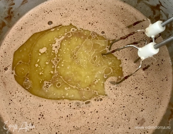 Взбить венчиком яйца, сахар, половину порции молока, минеральную воду. Добавить просеянные муку и какао. Перемешать, чтобы не было комочков. Вторую половину молока подогреть (довести почти до кипения). Добавить в тесто горячее молоко и растопленное масло, снова взбить. Тесто должно быть жидким.