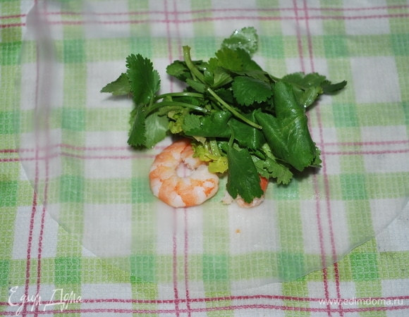 На льняное полотенце выложите лист, в центр листа выложите 2 креветки и свежую кинзу.