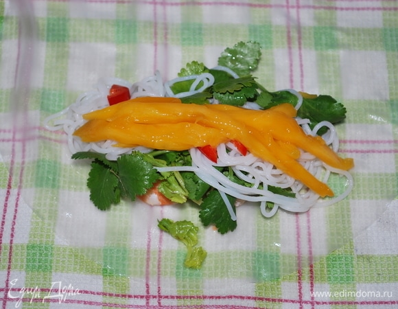 Сверху кинзы выложите 1/8 лапши, пару кружочков острого перца (по желанию) и свежий манго.