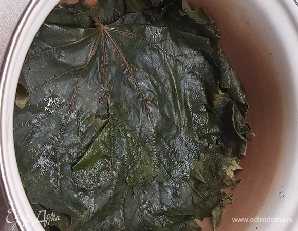 Дно кастрюли, в которой будет готовиться долма, выложить виноградными листьями.