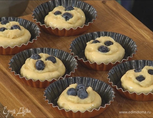 Охлажденное тесто разложить в формочки так, чтобы получились бортики, и смазать яйцом, в центр выложить по 1 ч. ложке крема и украсить ягодами голубики.