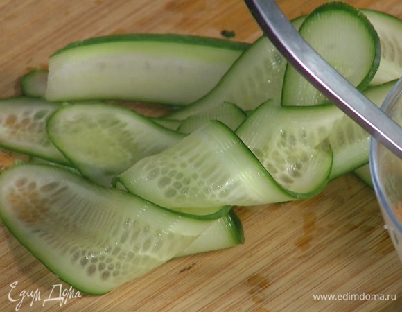 При помощи овощечистки нарезать огурец тонкими ломтиками.