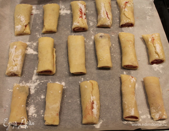 Противень застилаем бумагой для выпечки. Выкладываем мини-рулетики и слегка посыпаем их мукой. Ставим в разогретую до 170°C духовку примерно на 30 минут.