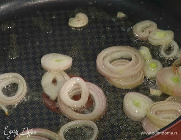 Разогреть сковороду с оливковым маслом. Нарезать лук кольцами, слегка обжарить. Чеснок раздавить плоской стороной ножа, целиком добавить в сковороду.