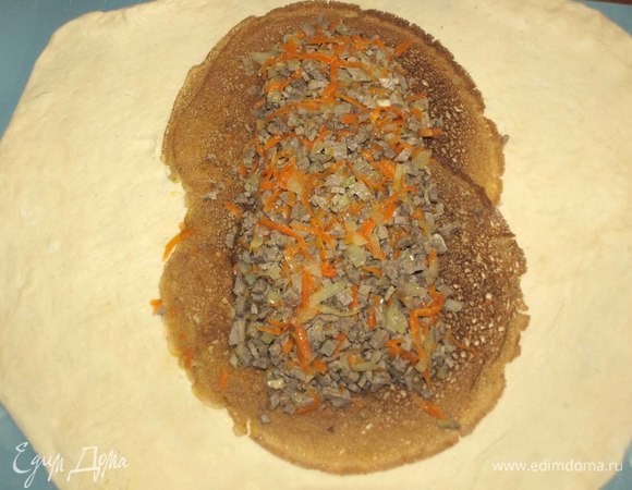 Готовое тесто тонко раскатываем на посыпанной мукой поверхности. Оставляем немного теста для украшения. Кладем на тесто два блина. Блины должны перекрывать друг друга. На блины кладем начинку из говядины, разравниваем.