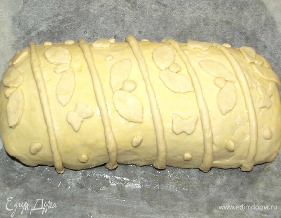 Переворачиваем кулебяку швом вниз. Кладем на противень, застеленный смазанной растительным маслом пекарской бумагой. Одно куриное яйцо взбить, немного смазать кулебяку, чтобы украшения хорошо держались. Украшаем остатками теста.