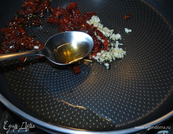 На оливковом масле обжарьте в течение 1–2 минут щепотку сухого базилика, чеснок и вяленые помидоры, нарезанные кусочками.