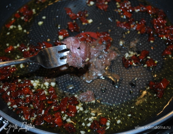 Добавьте 3 анчоуса и разомните их вилкой до образования пасты. Обжарьте все вместе 2–3 минуты.